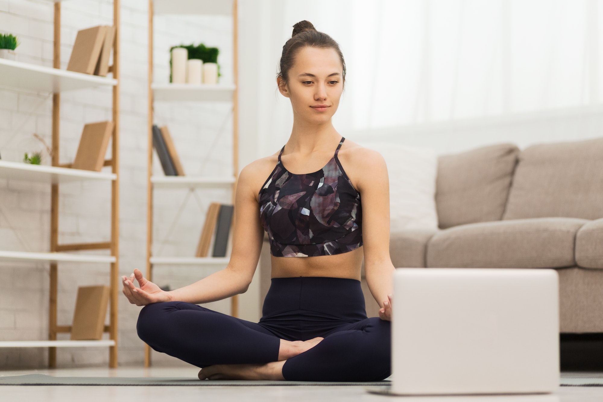 Sport application. Millennial woman practicing yoga at home
